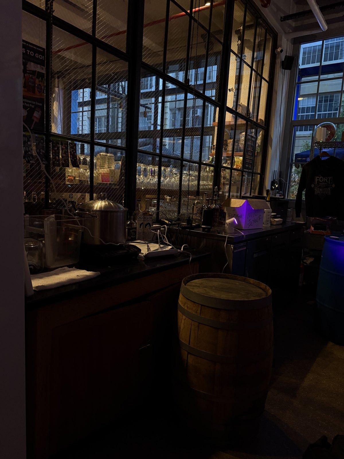 Fort Hamilton Distillery — barrel in the foreground, industrial windows looking out to Industry City beyond
